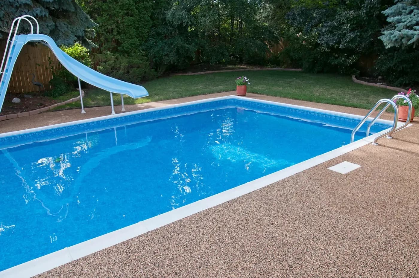 Rectangular backyard pool with a tan Rubber Stone deck